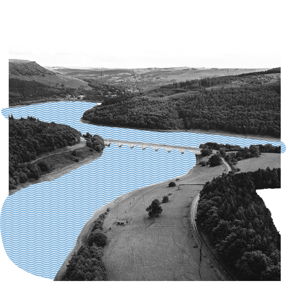 Ein Fluss schlängelt sich durch eine mit Auen, Feldern und Wäldern gesäumte Landschaft. Eine Brücke verbindet das eine Ufer mit dem anderen. 